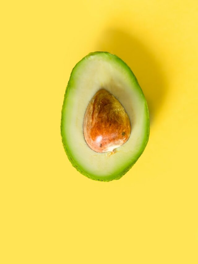 an avocado cut in half on a yellow background