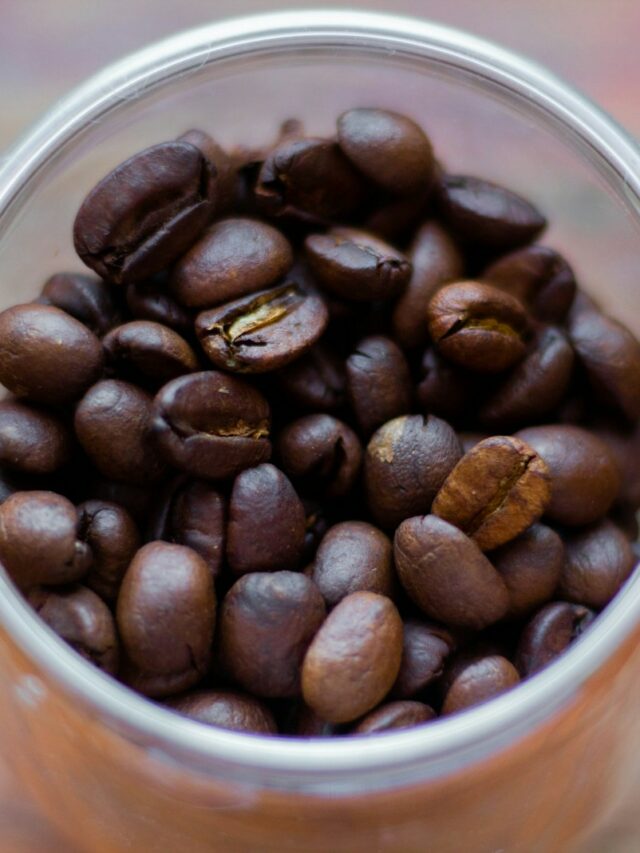 a cup filled with coffee beans on top of a wooden table