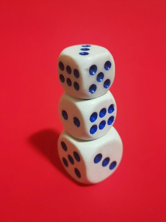 two dices stacked on top of each other on a red surface