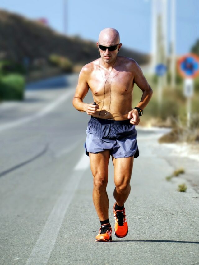 man jogging while listening using black earphones during day time