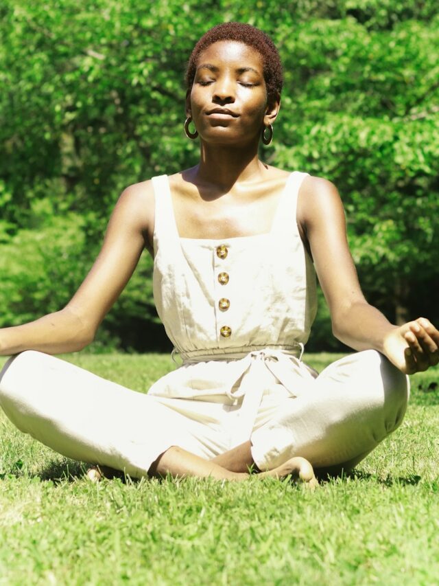 woman in white tank top sitting on green grass field during daytime