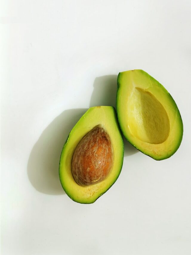 an avocado cut in half on a white surface