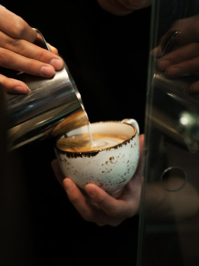 person holding clear glass cup with white liquid