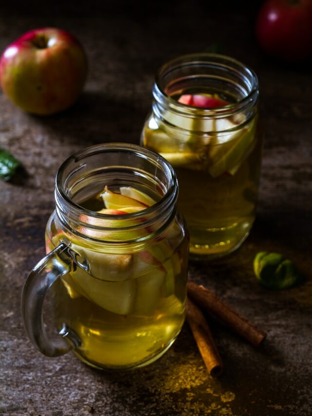 two drinking glasses filled with apple juice