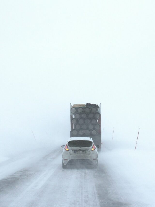 white car behind a truck on snowy road