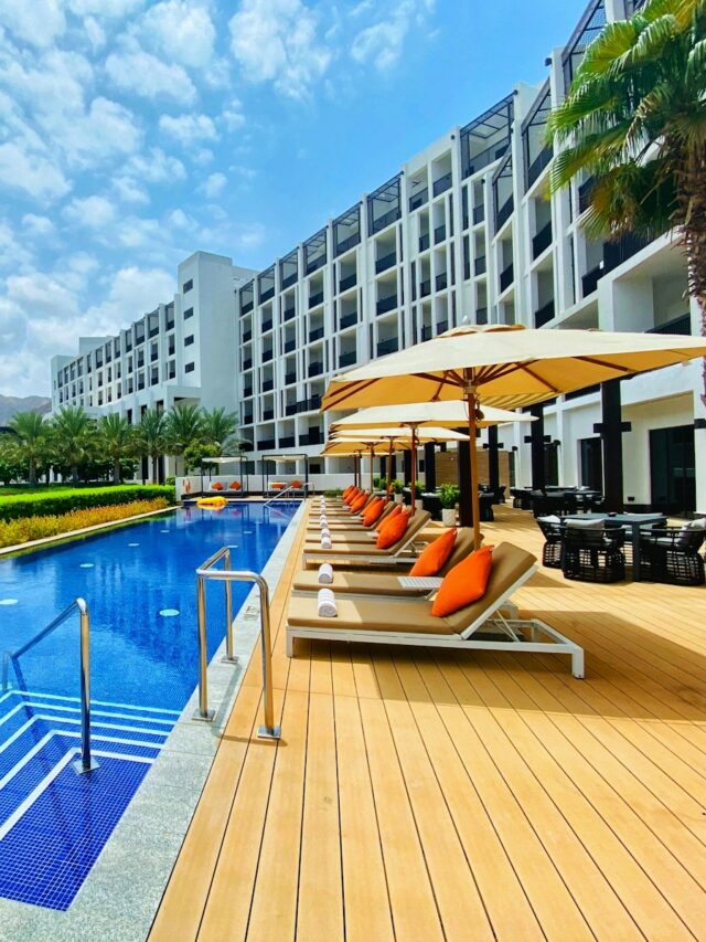 white and brown wooden lounge chairs near swimming pool during daytime